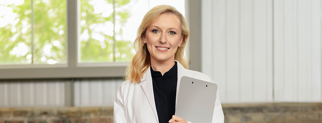 Image of hearing care professional holding clipboard and smiling